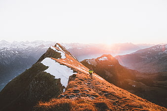 Hiker on Snowy Mountain Ridge at Golden Hour
