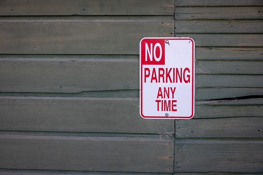 No Parking Any Time Sign on Weathered Green Wood Wall