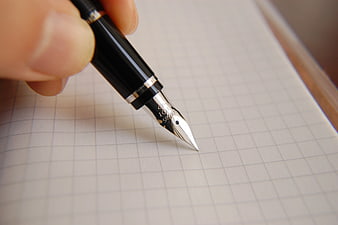 Close-up of black fountain pen writing on grid paper
