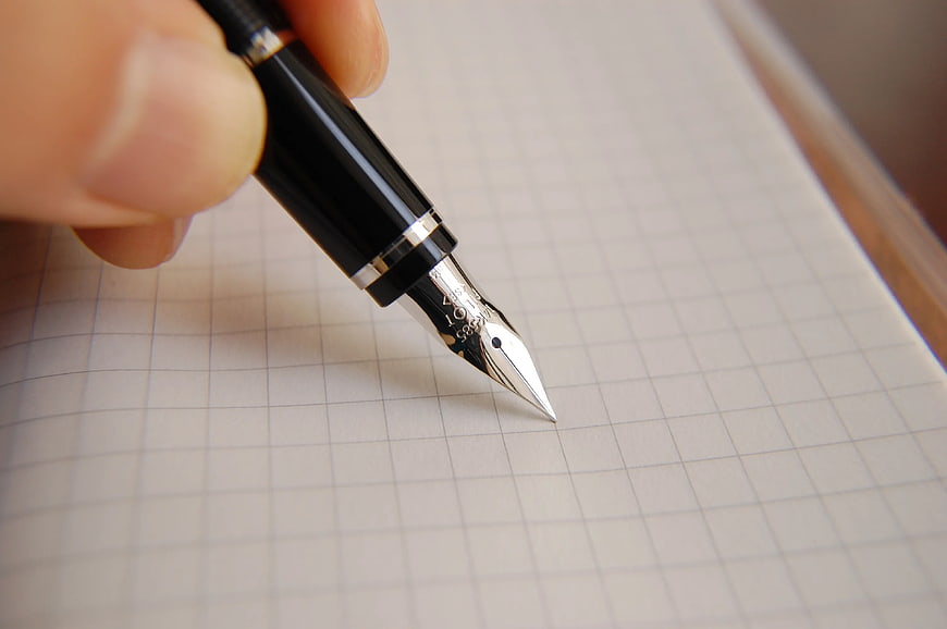 Close-up of black fountain pen writing on grid paper