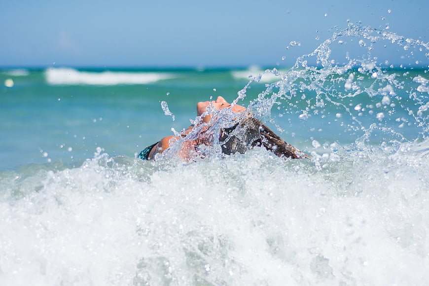 Woman splashing in ocean waves on sunny beach