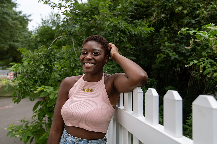 Happy Black Woman Smiling by White Fence