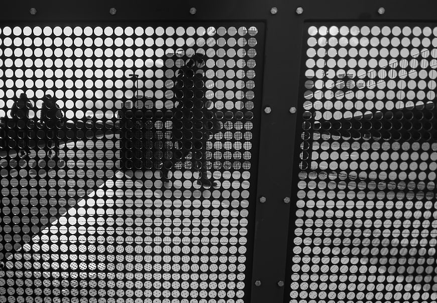 Black and white perforated metal screen with urban reflections