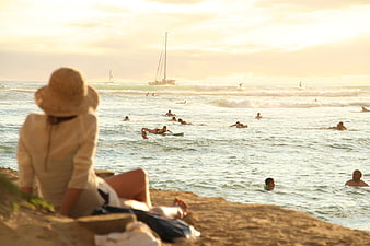 Woman in Straw Hat Watching Surfers at Sunset Beach