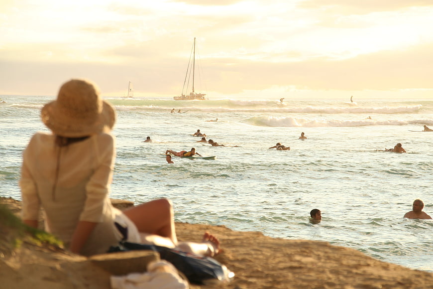 Woman in Straw Hat Watching Surfers at Sunset Beach
