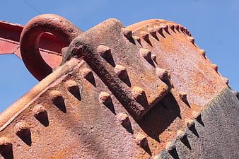 Close-up of Rusted Metal Buoy with Rivets Against Blue Sky