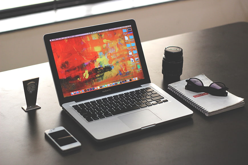 Modern workspace with laptop, camera lens, and smartphone on desk