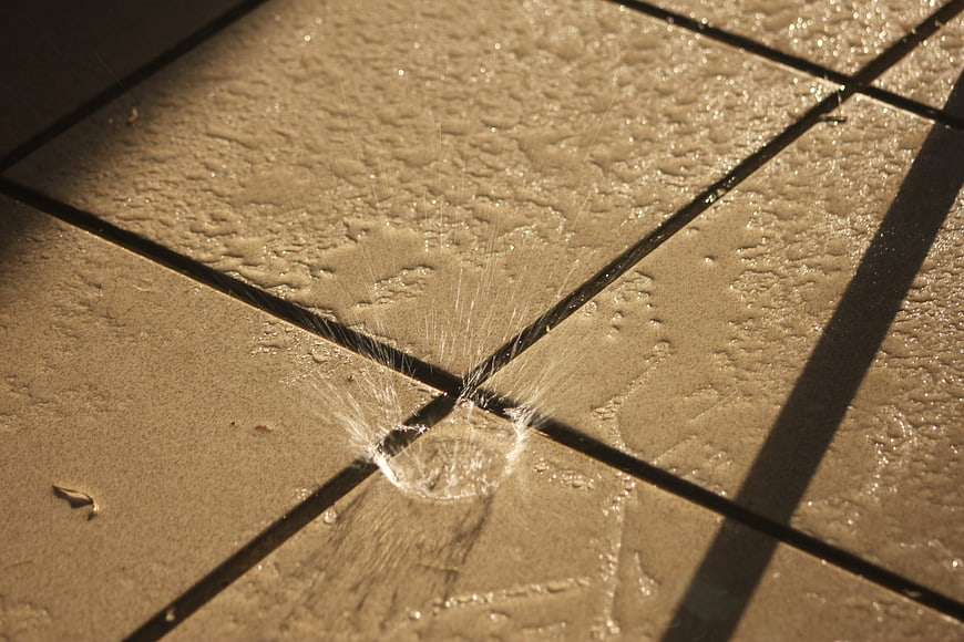 Water droplet splash on textured beige tiles