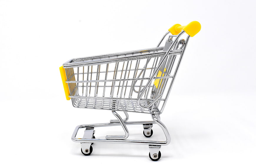 Miniature metal shopping cart with yellow handles on white background