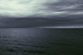 Lone Sailboat on Dark Ocean Under Stormy Clouds
