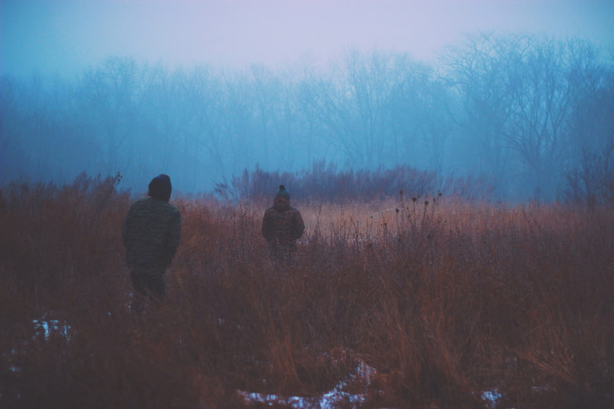 Two people walking in foggy winter field