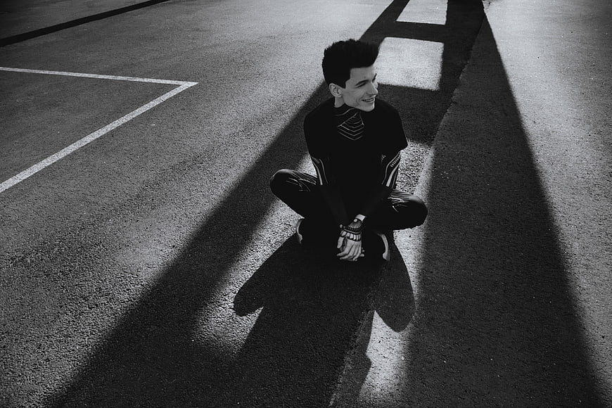 Man Sitting in Shadows on Asphalt