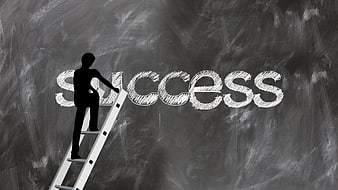 Silhouette of person climbing ladder to reach success word on chalkboard