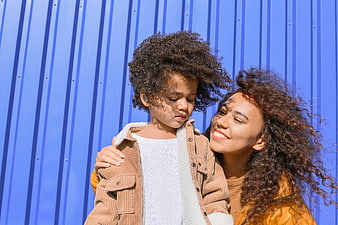 Mother and child hugging against blue corrugated wall