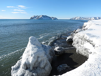 Frozen Rocks on Snowy Winter Coastline with Island
