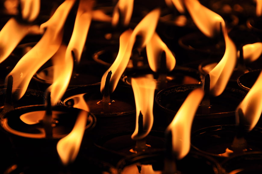 Close-up of burning oil lamps in a dark temple setting