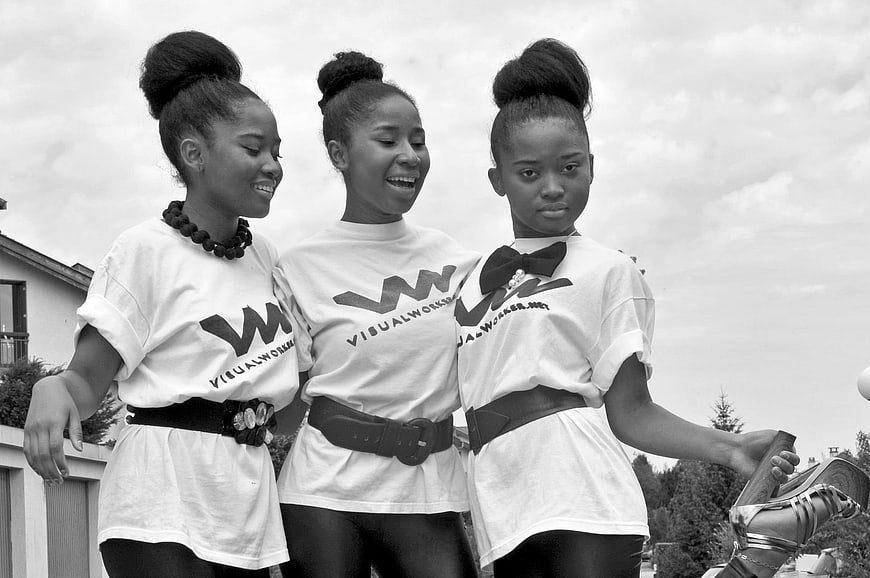 Three young women in matching t-shirts smiling outdoors