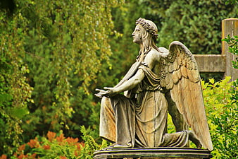 Kneeling Stone Angel Statue In Green Cemetery Garden