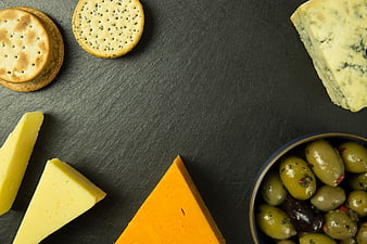 Flat lay cheese board with crackers and olives on slate