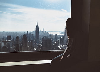 Silhouette of Woman Looking Out Window at City Skyline