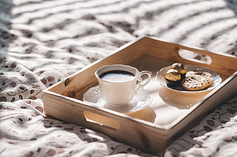 Wooden tray with coffee and cookies on bed