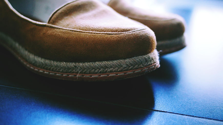 Close-up of brown suede loafers on blue surface