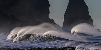 Dramatic ocean waves crashing against dark coastal cliffs