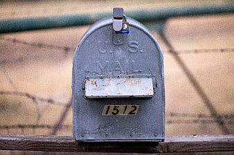 Vintage U.S. Mailbox with Rusty Flag on Wooden Fence