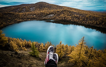 Hiker's feet overlooking turquoise lake in autumn forest