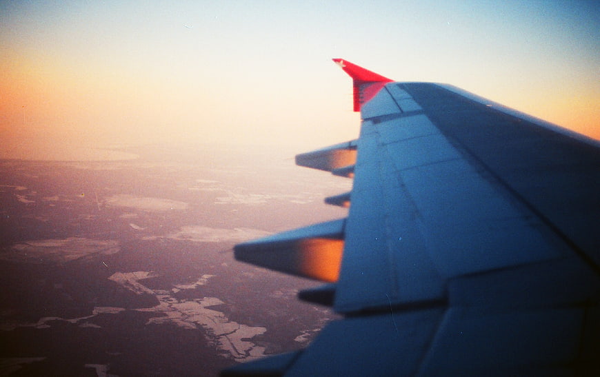 Airplane Wing View at Sunset Over Landscape