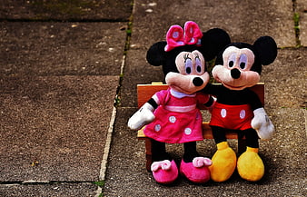 Mickey and Minnie Mouse plush toys sitting on a bench