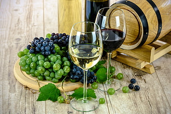 Red and white wine glasses with grapes and barrel
