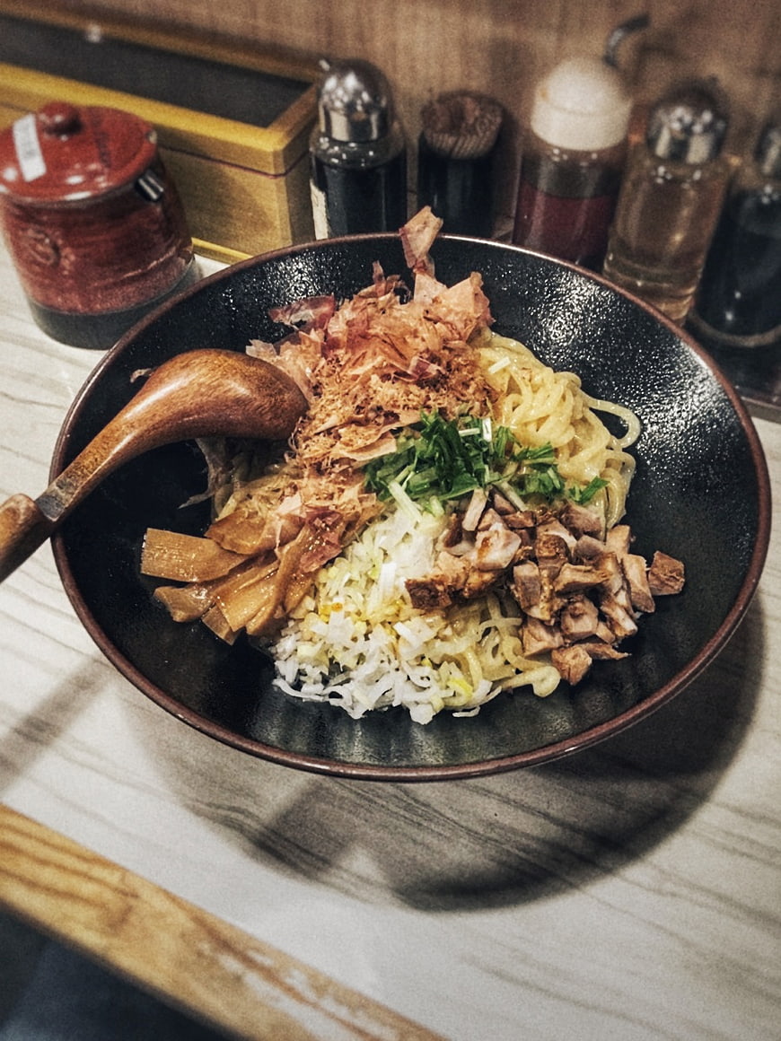 Bowl of Japanese Ramen with Toppings and Wooden Spoon