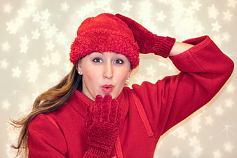 Woman in red winter coat blowing a kiss against starry background