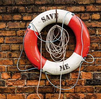 Vintage red and white lifebuoy with save me text on brick wall