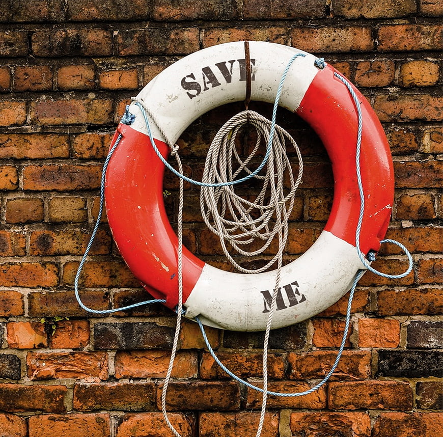 Vintage red and white lifebuoy with save me text on brick wall