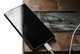 Black Smartphone Charging on Rustic Wooden Table
