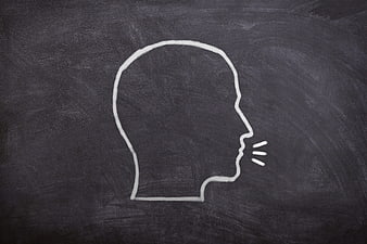 White chalk silhouette of a human head speaking on a blackboard