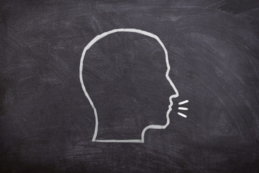 White chalk silhouette of a human head speaking on a blackboard