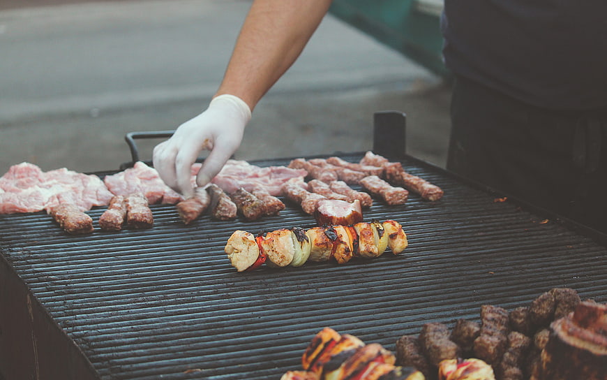 Chef grilling meat and vegetable kebabs on outdoor barbecue