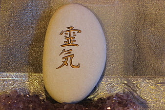 White stone with gold Reiki kanji characters on textured fabric