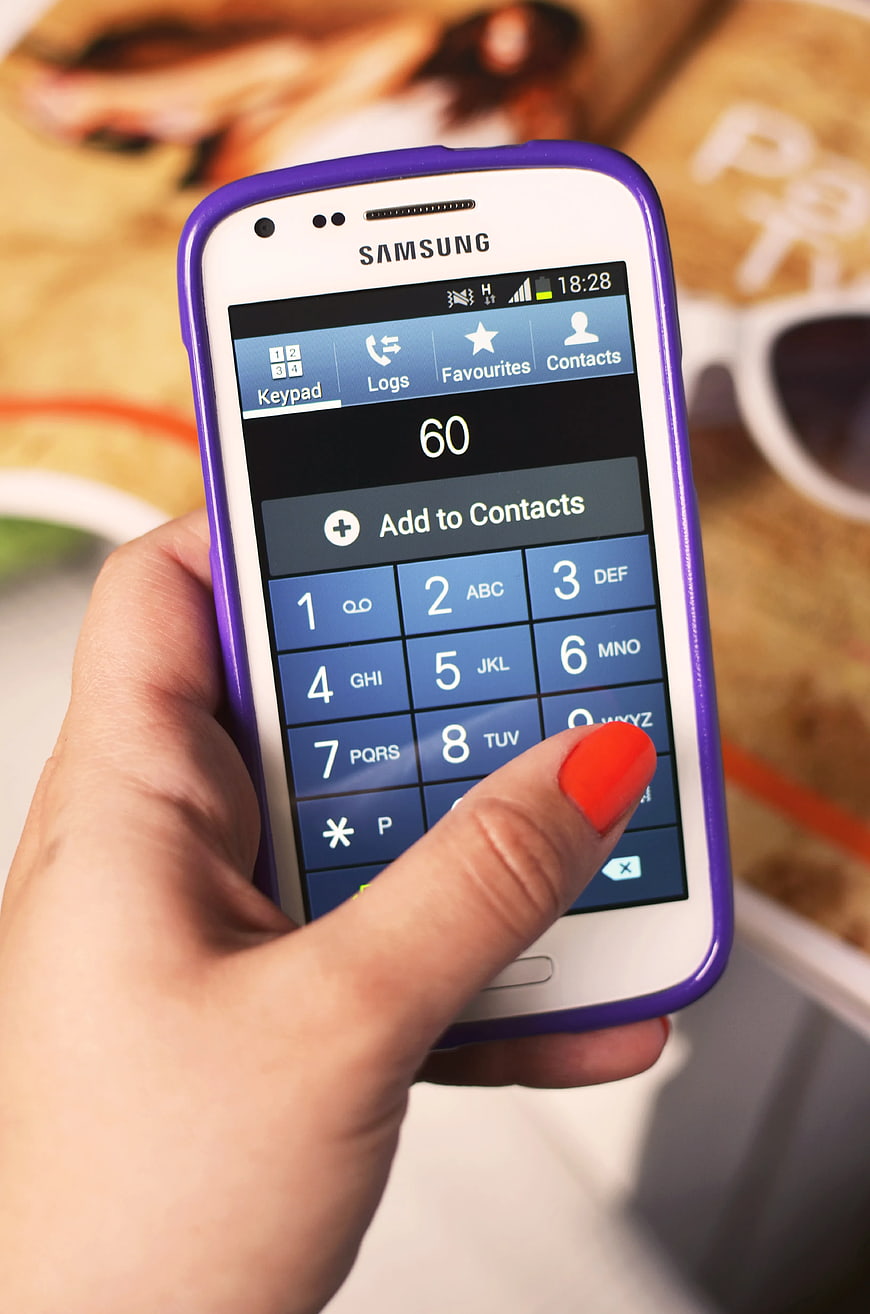 Hand holding white Samsung smartphone with purple case