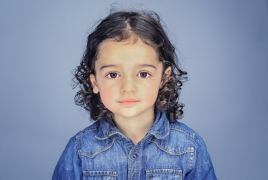 Studio Portrait of Young Girl with Curly Hair in Denim Shirt