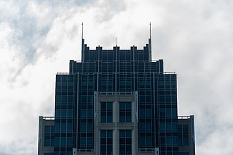 Modern Glass Skyscraper Against Cloudy Sky