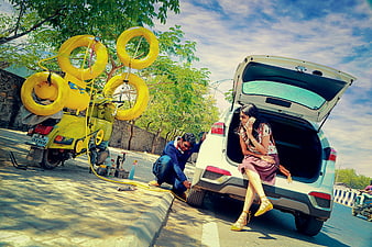 Woman waiting while mechanic fixes car tire roadside