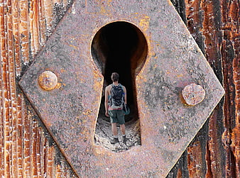 Hiker Entering Rusty Keyhole Doorway In Industrial Wall