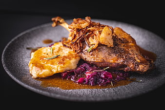 Roast Duck Leg with Caramelized Onions and Red Cabbage on Dark Plate