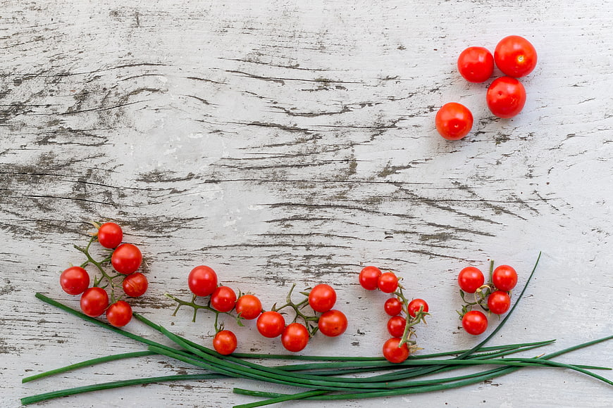 Fresh cherry tomatoes and chives on rustic white wood
