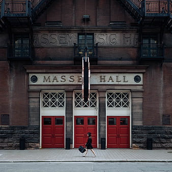 Woman walking past Massey Hall red doors in Toronto