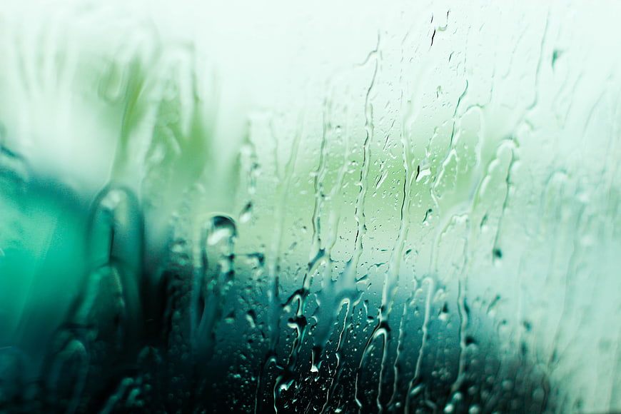 Raindrops on a glass window with a blurred green background